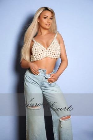 Girl with long blonde hair in a pair of baggy torn jeans and white tank top