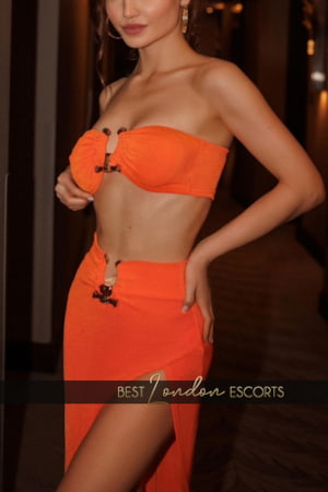 A slim elegant brunette in a striking orange outfit