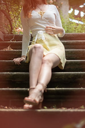 Elegant young girl in a summery yellow skirt sitting in a garden