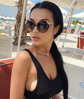Busty British girl with black hair sitting in a sunny resort