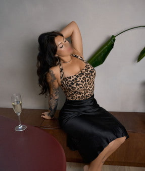 Beautiful dark haired woman in a leopard print top next to a glass of champagne