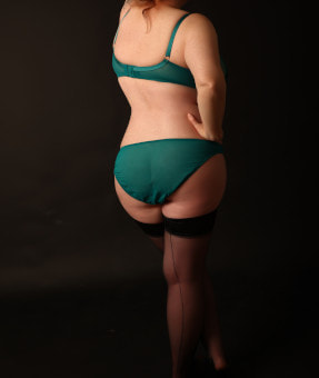 Curvy blonde woman in green panties with her back to the camera