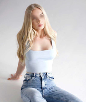 Beautiful young blond in jeans sitting on a white floor