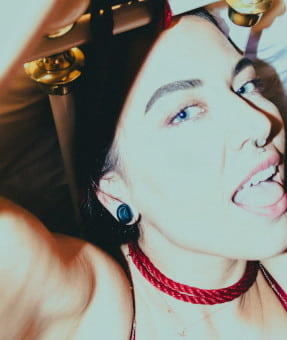 Close up photo of a blue-eyed brunette with a nose piercing