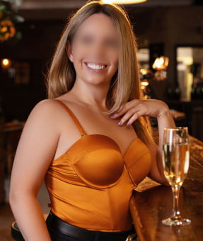 Smiling blonde lady standing at a wooden bar
