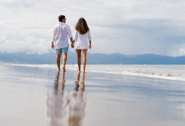 A couple walking hand in hand on an empty golden beach